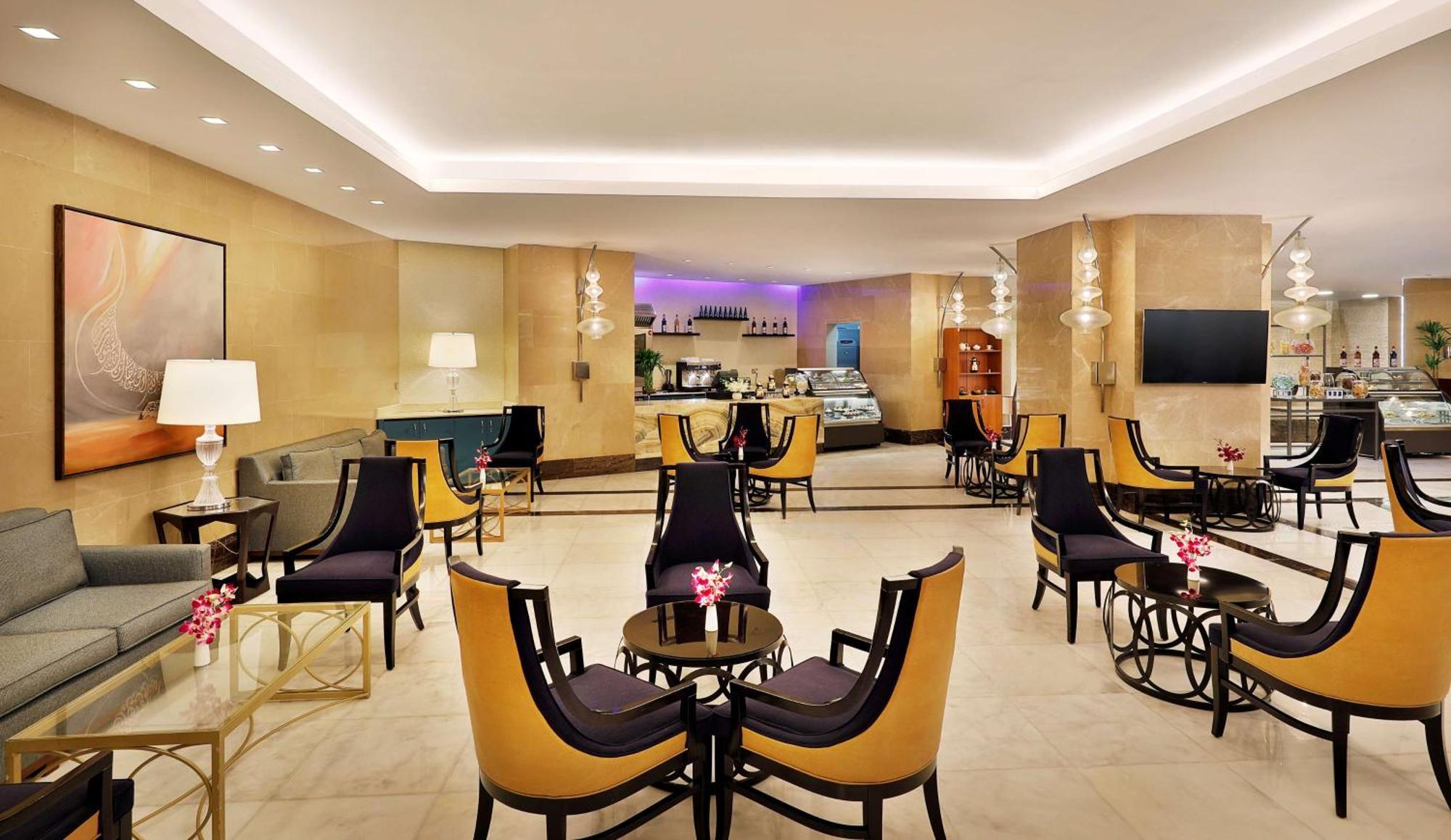 Hilton Suites Jabal Omar Makkah Mekka Exteriér fotografie The photo depicts a stylish and contemporary lounge area, featuring elegant furniture arranged in a cozy setting. There are several black and gold accent chairs with small glass tables in front of them, creating small seating groups. The decor includ